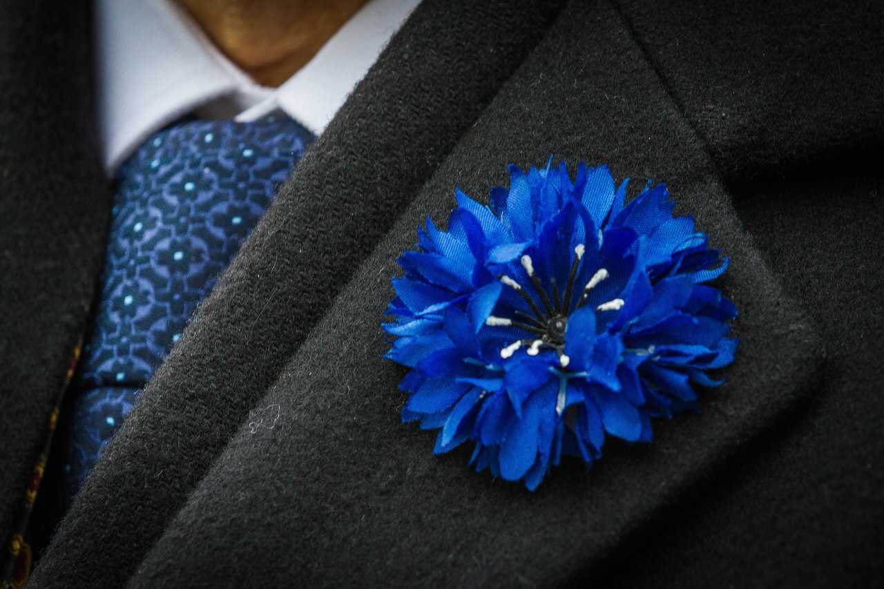Bleuet de France contemporain en pin de boutonnière, novembre 2013, emblème mémoriel officiel français porté chaque 11 novembre et 8 mai au profit de l'Office national des combattants et victimes de guerre, héritier direct du geste fondé en 1925 aux Invalides