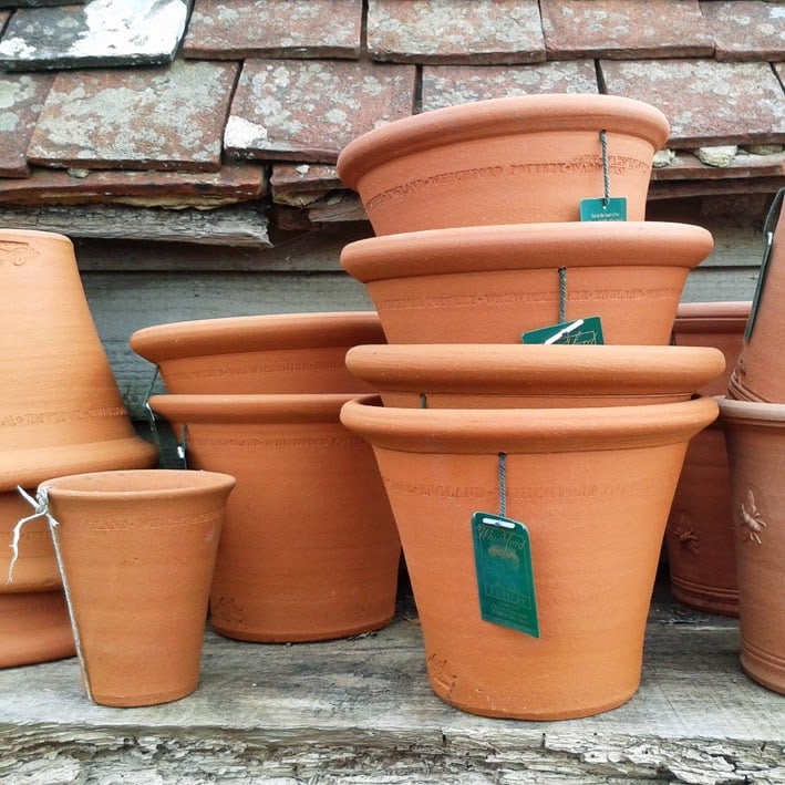 Pots en terre cuite rouge empilés, chacun percé d'un trou de drainage au fond