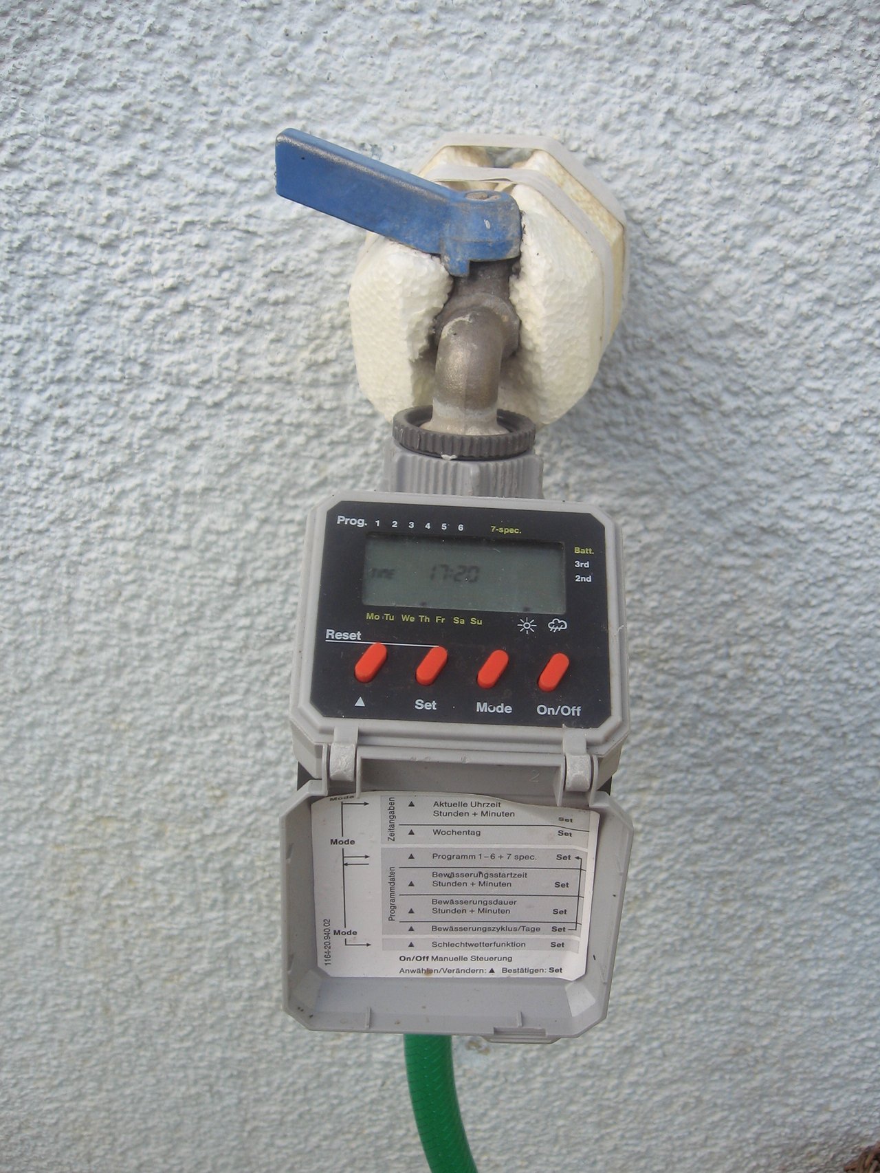 Programmateur d'arrosage Gardena vissé sur un robinet extérieur, écran LCD affichant l'horaire de cycle