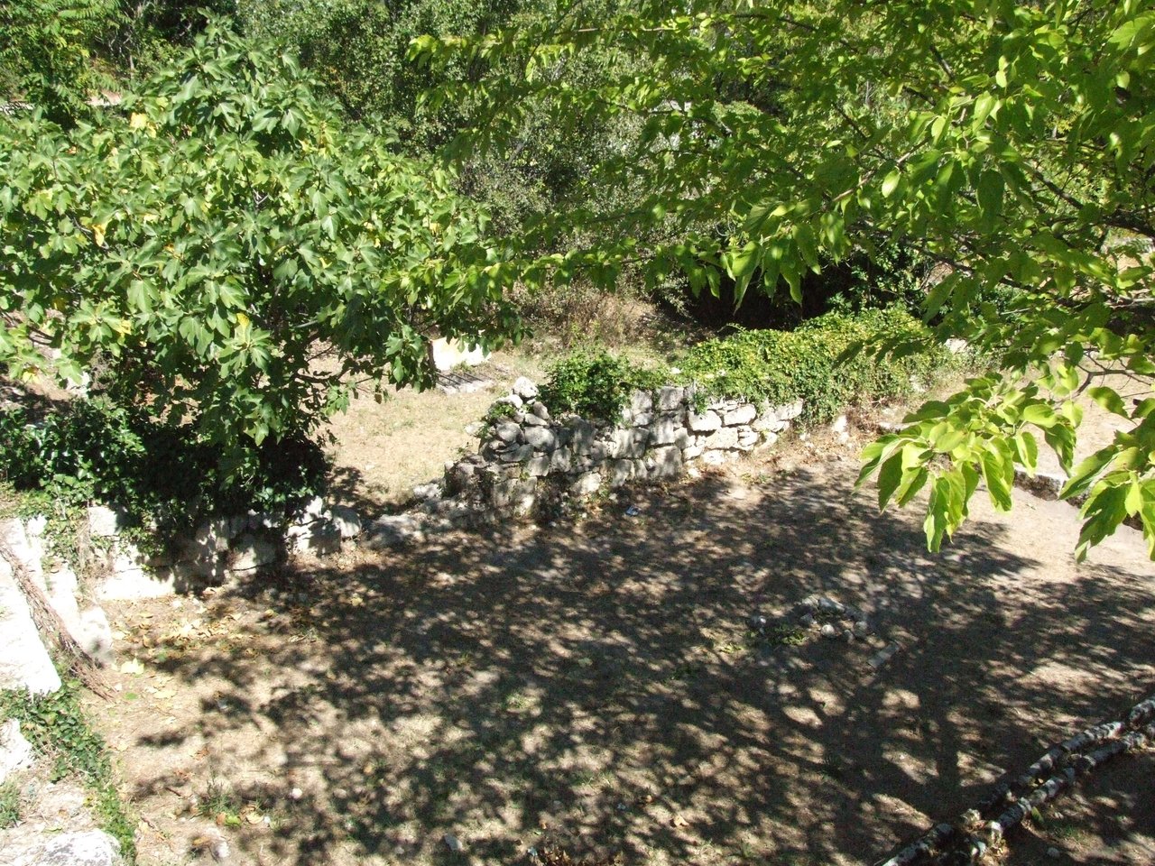 Vue en plongée de jardins familiaux à Junas dans le Gard : parcelles maraîchères en bandes, allées entre carrés, mosaïque de cultures