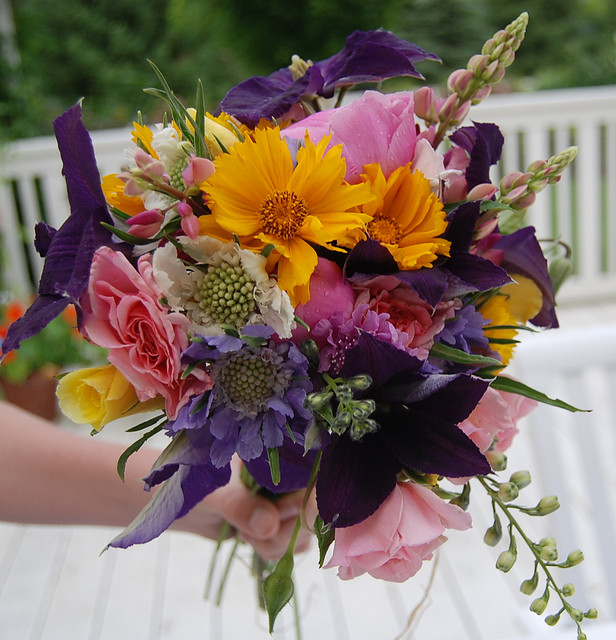 Bouquet varié de fleurs fraîchement coupées tenu à la main au-dessus d'un banc