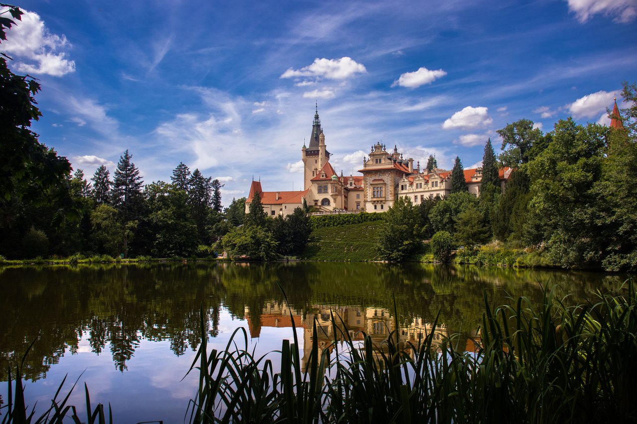 Pohled na zámek a rybník Průhonického parku v letní zeleni